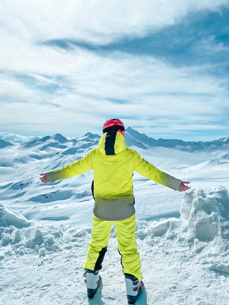 Ein glücklicher Teenager in einem hellen Sport-Ski-Anzug in den Bergen