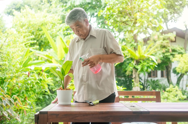 Ein glücklicher und lächelnder asiatischer alter älterer mann pflanzt nach dem ruhestand in einem haus für ein hobby. konzept eines glücklichen lebensstils und einer guten gesundheit für senioren.