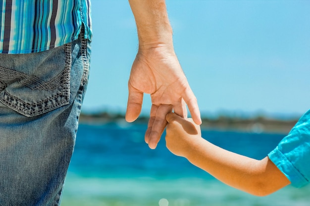 Ein glücklicher Vater hält die Hand eines Kindes am griechischen Meer in der Natur