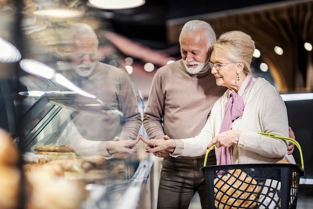 Ein glückliches älteres Paar kauft Gebäck im Supermarkt ein