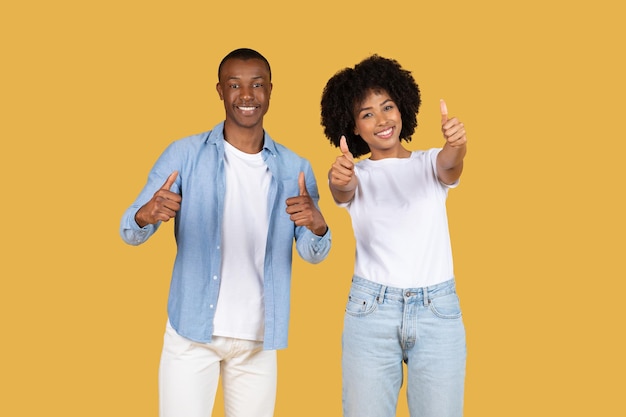 Ein glückliches afrikanisch-amerikanisches Paar, das mit dem Mann in blauem Hemd und weißer Hose den Daumen hochgibt