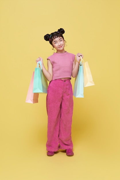 Ein glückliches asiatisches Kind, das farbenfrohe Einkaufstaschen trägt und zum Supermarkt geht