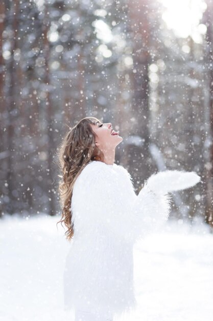Ein glückliches, fröhliches Mädchen in einem warmen Pelzmantel geht im Winterwald spazieren