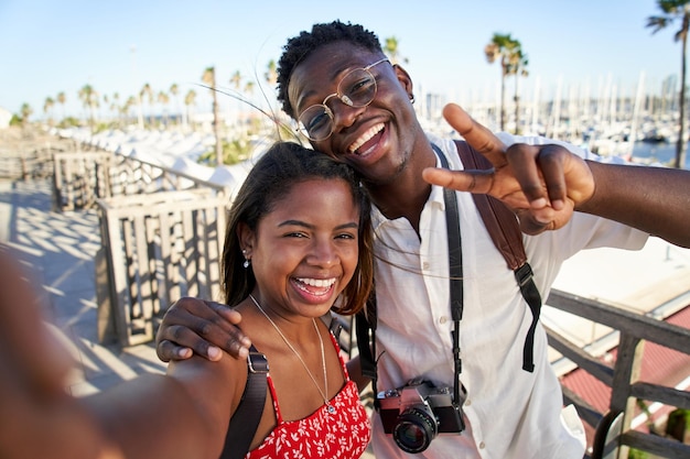 Ein glückliches junges afrikanisches Touristenpaar genießt den Sommerurlaub in einem Ferienort an der Küste und macht Selfies