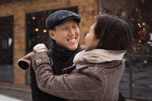 ein glückliches junges asiatisches paar trifft sich in winterstadt steet für ein date