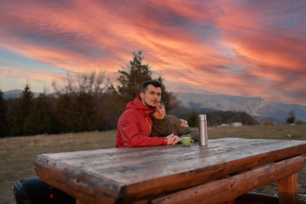 Ein glückliches junges muslimisches Paar entspannt sich bei einer Tasse Kaffee in der Natur bei Sonnenuntergang im Urlaub