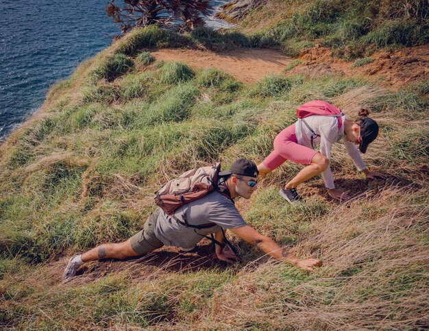 Ein glückliches junges Paar klettert in den Bergen nahe dem Meer auf den Gipfel