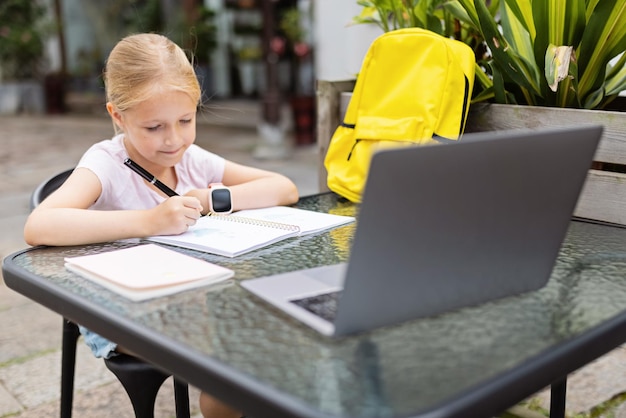 Foto ein glückliches kaukasisches kind hat während der coronavirus-pandemie und des lockdowns einen online-unterricht auf einem laptop.