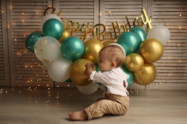 Ein glückliches Kind auf dem Hintergrund von Ballons mit Girlanden feiert seinen Geburtstag