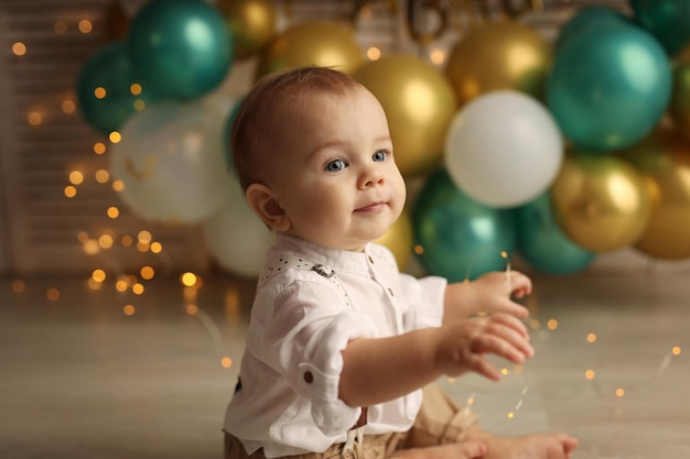 Ein glückliches Kind auf dem Hintergrund von Ballons mit Girlanden feiert seinen Geburtstag