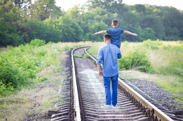 Ein glückliches Kind auf den Schultern eines Elternteils in der Natur auf dem Weg zum Reisen