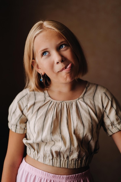 Foto ein glückliches kind, ein kleines mädchen in einem grauen t-shirt auf beigem hintergrund