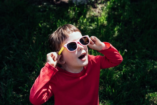 Ein glückliches Kind mit offenem Mund, das mit Sonnenbrille in die Sonne schaut