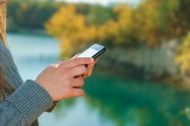 Ein glückliches Kind mit Telefon, das Selfie in der Natur in der Parkreise macht