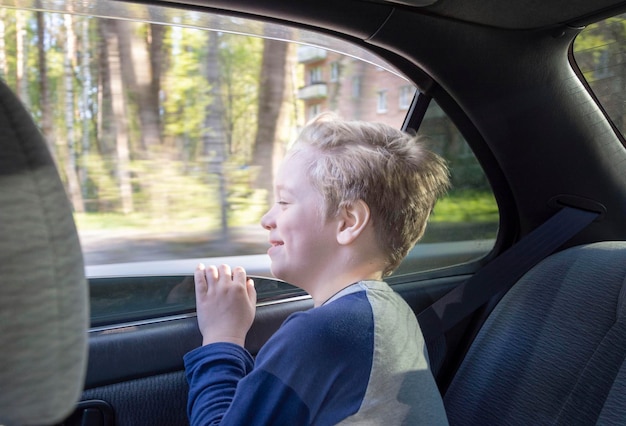 Ein glückliches Kind schaut aus einem offenen Autofenster unterwegs einen Blick aus dem Auto