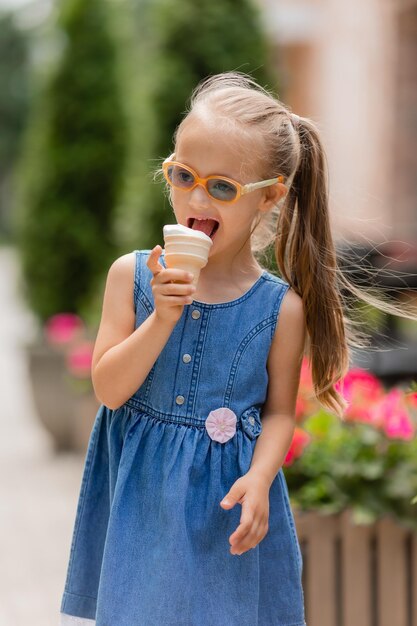 ein glückliches kleines Mädchen mit Down-Syndrom isst im Sommer Eis auf einem Spaziergang