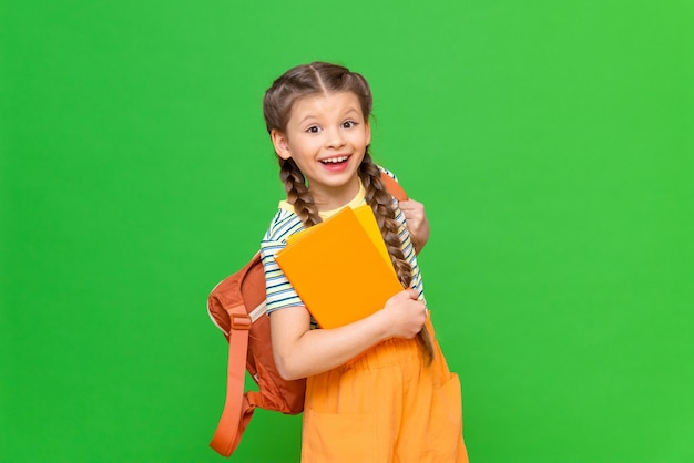 Ein glückliches kleines Schulmädchen mit Lehrbüchern und einer Aktentasche auf einem isolierten Hintergrund. Platz kopieren.