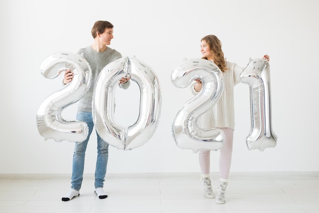 Ein glückliches Liebespaar hält silberne 2021 Luftballons