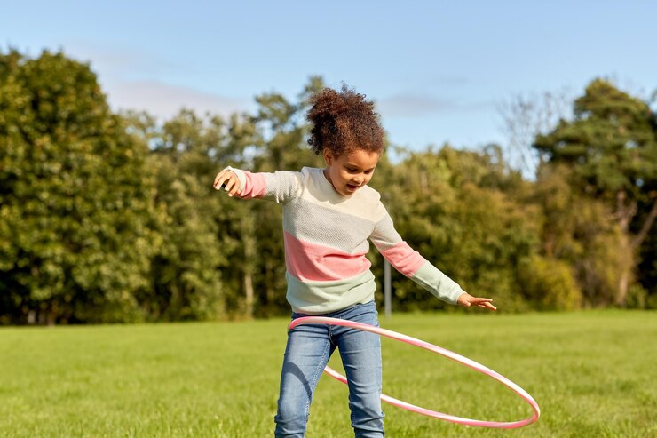 Foto ein glückliches mädchen spielt mit hula-hoop im park