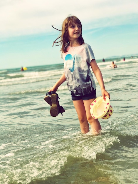 Ein glückliches Mädchen steht am Ufer am Strand