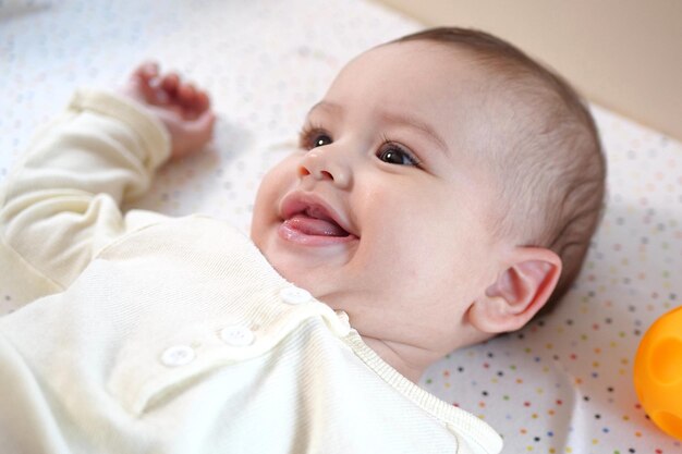 Ein glückliches Neugeborenes macht ein lustiges Gesicht Porträt eines krabbelnden Babys in seinem Zimmer auf Nahaufnahme