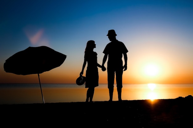 Ein glückliches Paar am Meer bei Sonnenuntergang auf Reisesilhouette in der Natur