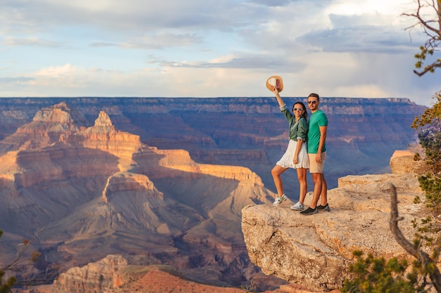 Ein glückliches Paar auf einer steilen Klippe, das die atemberaubende Aussicht auf den berühmten Grand Canyon bei einem wunderschönen Sonnenuntergang genießen, Grand Canyon National Park Arizona USA