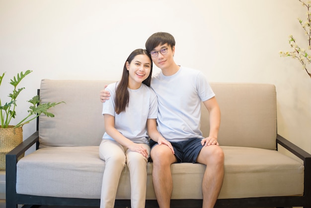Ein glückliches Paar, das blaues Hemd trägt, sitzt zu Hause auf einem Sofa