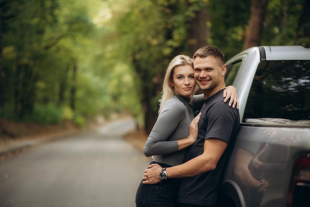 Foto ein glückliches paar in der nähe des autos im wald