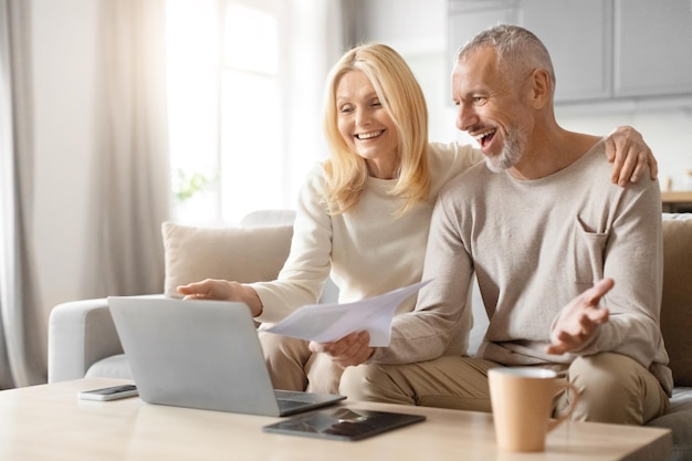 Foto ein glückliches paar mit papieren und laptop diskutiert