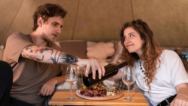 Ein glückliches Paar ruht sich in einem Zelt beim Glamping Wein und Essen aus