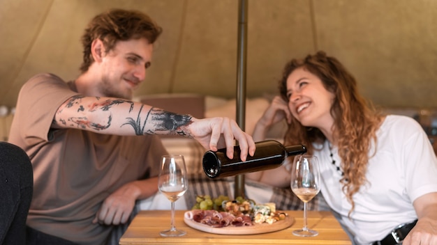 Ein glückliches Paar ruht sich in einem Zelt beim Glamping Wein und Essen aus