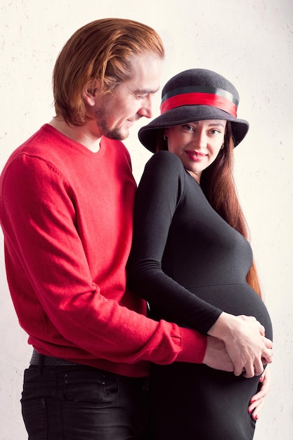 Foto ein glückliches paar schwangeres mädchen, das mit ihrem mann steht und sich selbst zusammenhält