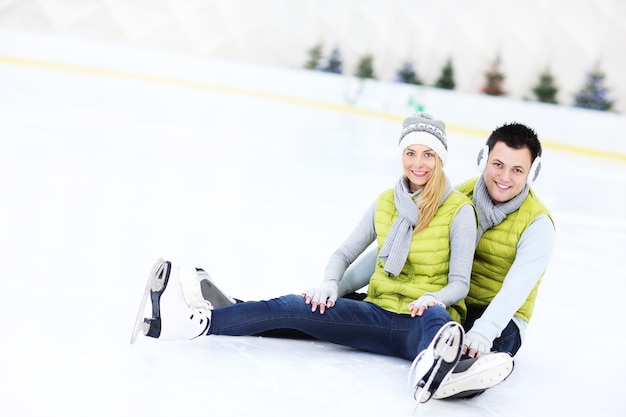 ein glückliches Paar sitzt auf der Eisbahn