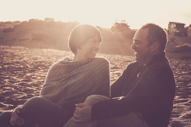 Ein glückliches Paar sitzt bei Sonnenuntergang am Strand