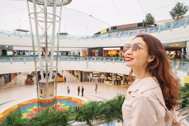 Ein glückliches, stilvolles asiatisches Mädchen, das im Einkaufszentrum einkaufen geht.