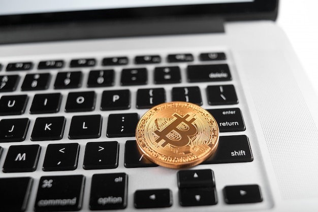 Ein goldenes Bitcoin als Welthaupt-Kryptowährung, platziert auf Laptoptastatur.