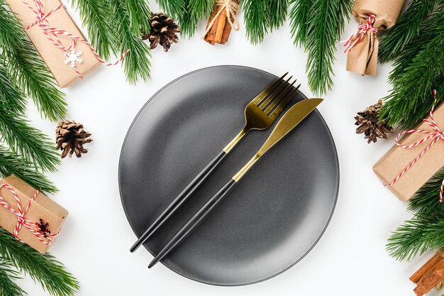 Ein goldenes Messer und eine Gabel auf einer schwarzen Keramikplatte auf dem gedeckten Tisch das Konzept einer Weihnachtsfeier i...