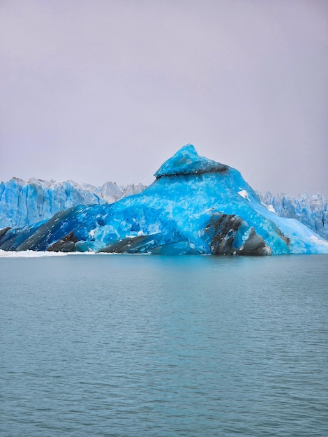 Foto ein großer blauer eisberg befindet sich in der nähe eines berges im wasser