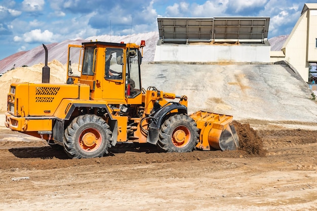 Ein großer Frontlader schüttet auf einer Baustelle Sand in einen Haufen Transport von Schüttgütern Baumaschinen Transport von Schüttgütern Aushub