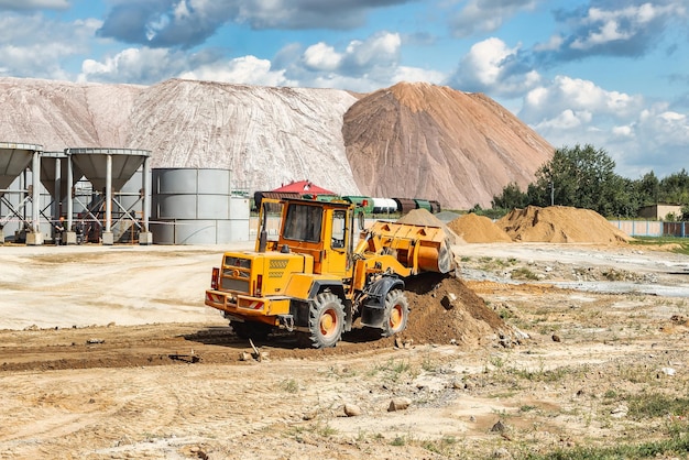 Ein großer Frontlader schüttet auf einer Baustelle Sand in einen Haufen Transport von Schüttgütern Baumaschinen Transport von Schüttgütern Aushub