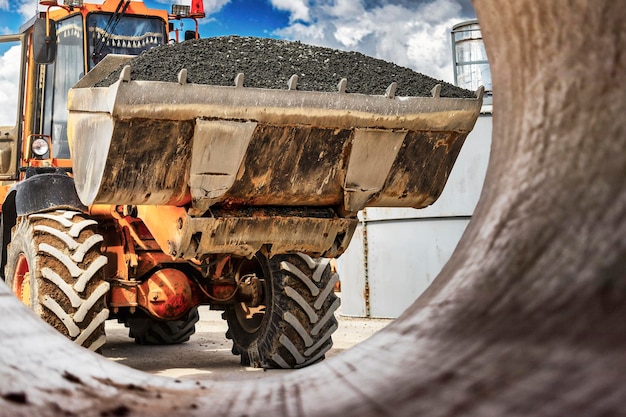 Ein großer Frontlader transportiert Schotter oder Kies in einem Eimer auf einer Baustelle oder einem Betonwerk Transport von Schüttgütern Baumaschinen Transport von Schüttgütern