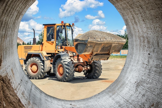 Ein großer Frontlader transportiert Schotter oder Kies in einem Eimer auf einer Baustelle oder einem Betonwerk Transport von Schüttgütern Baumaschinen Transport von Schüttgütern