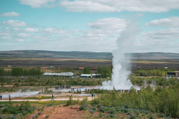 Ein großer Geysir mit blauem Himmel und Bergen im Hintergrund