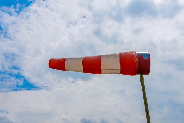 Ein großer rot-weiß gestreifter Windsack vor blauem Himmel