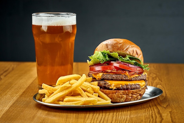 Ein großer saftiger Burger mit Gemüse und einem Glas Bier Selektiver Fokus der Nahaufnahme
