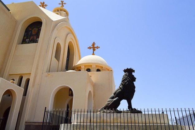 Foto ein großer schwarzer steinlöwe auf dem hintergrund einer ägyptischen orthodoxen weißen kirche mit kreuzbögen