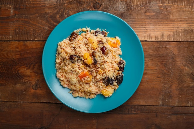 Ein großes Gericht aus Couscous mit getrockneten Früchten, Safran und Nüssen auf einem Holztisch