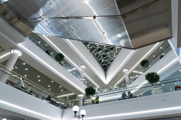 Ein großes mehrstöckiges Einkaufszentrum mit Rolltreppen und Aufzügen Blick in das Innere des Flughafens mit Zierpflanzen und großen Lampen