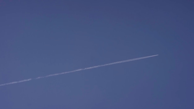Ein großes Passagier-Überschallflugzeug fliegt hoch in den klaren blauen Himmel und hinterlässt ein langes weißes Schleppflugzeug